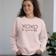 Woman wearing a light pink sweatshirt with 'XOXO The original love letters' text.