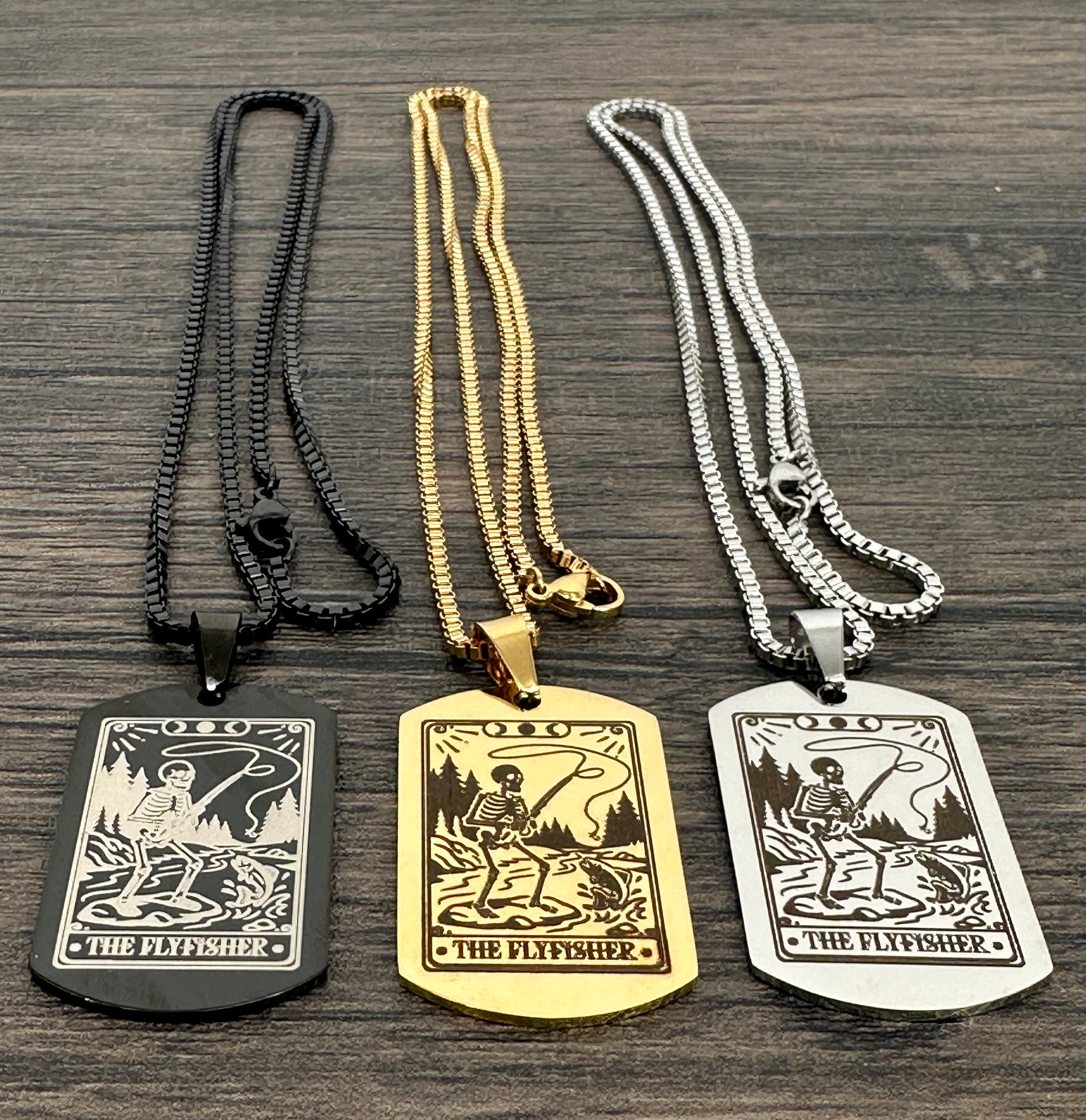 Three necklaces with 'The Flyfisher' pendant on a wooden surface