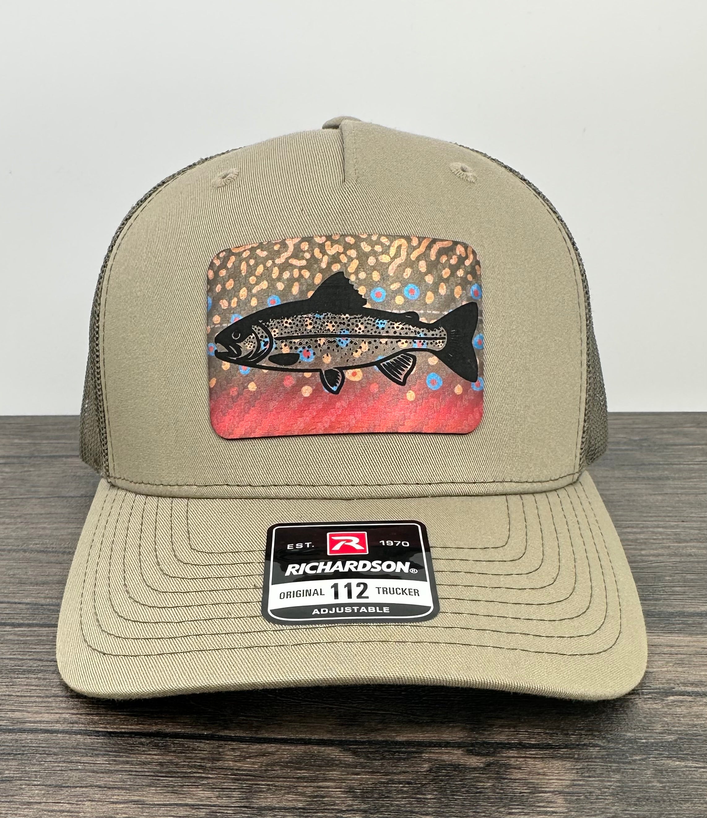 Beige hat with a brook trout printed patch with a trout laser engraved on the patch