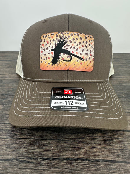 A brown and beige fly fishing hat with a laser engraved fly on a brown trout printed patch