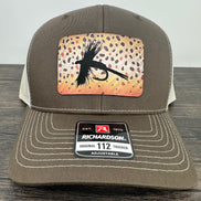 A brown and beige fly fishing hat with a laser engraved fly on a brown trout printed patch