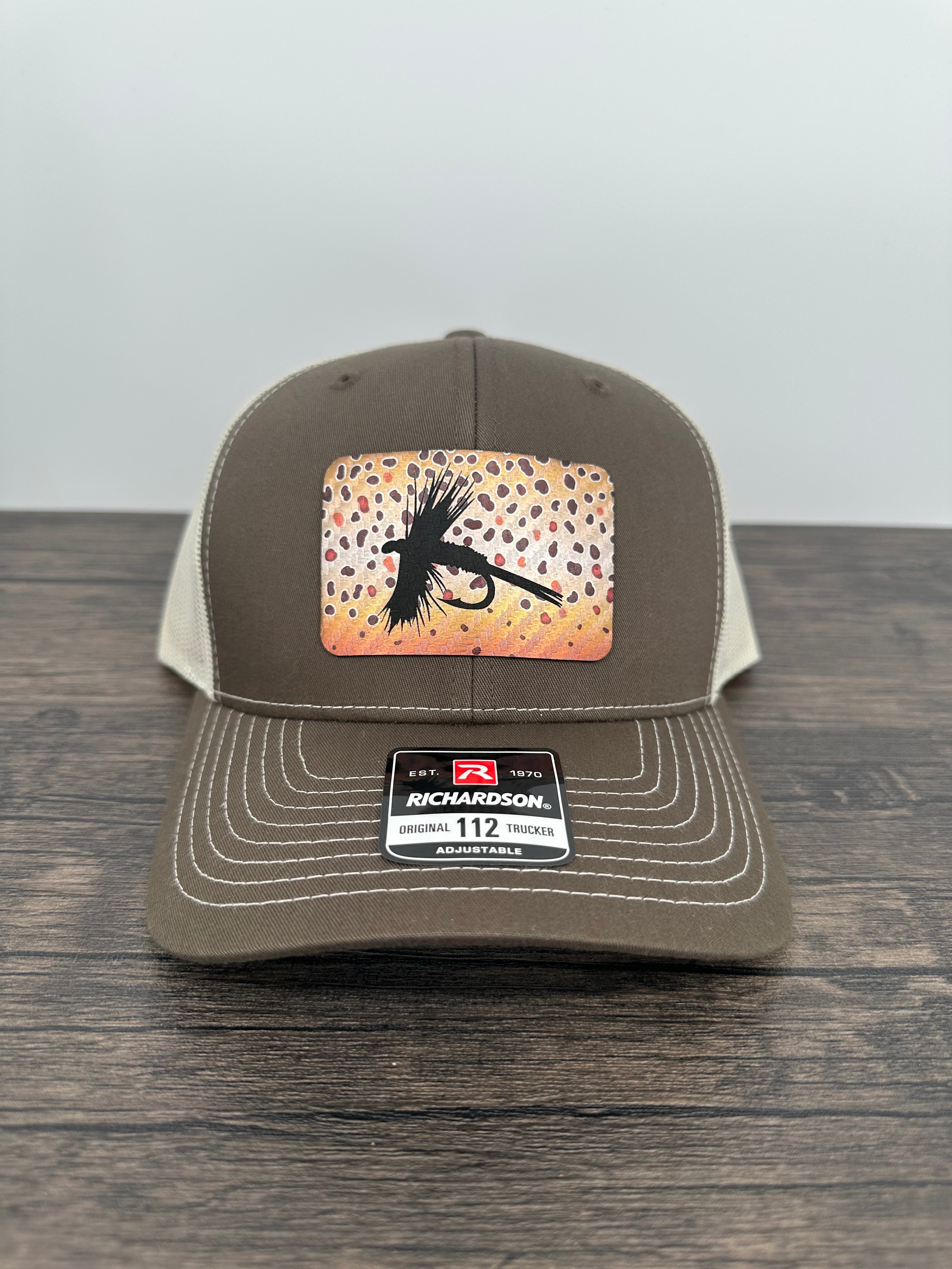A brown and beige fly fishing hat with a laser engraved fly on a brown trout printed patch