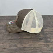Side view of A brown and beige fly fishing hat with a laser engraved fly on a brown trout printed patch