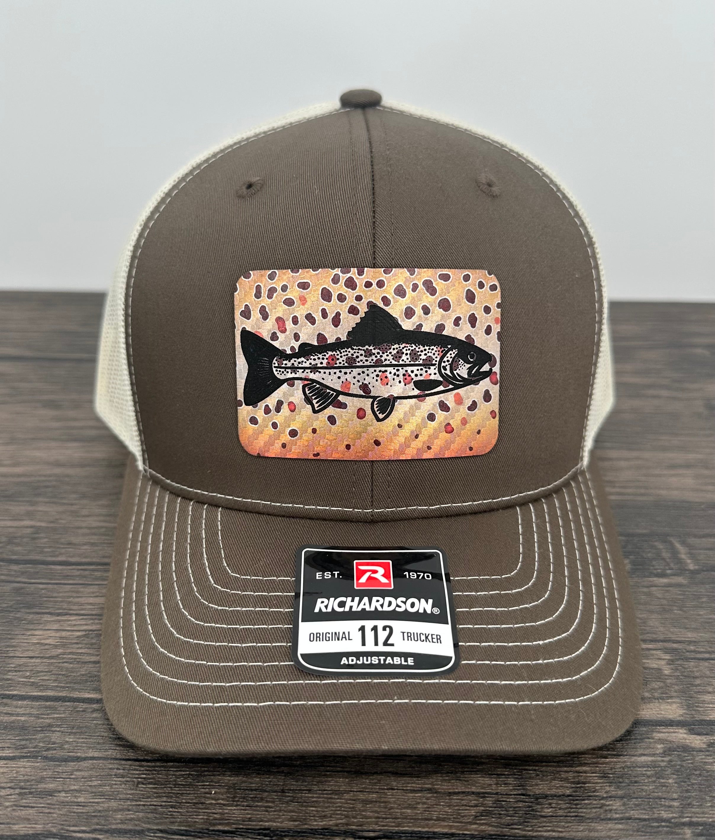 Brown and beige brown trout fly fishing hat featuring a laser engraved trout outline on a printed brown trout patch