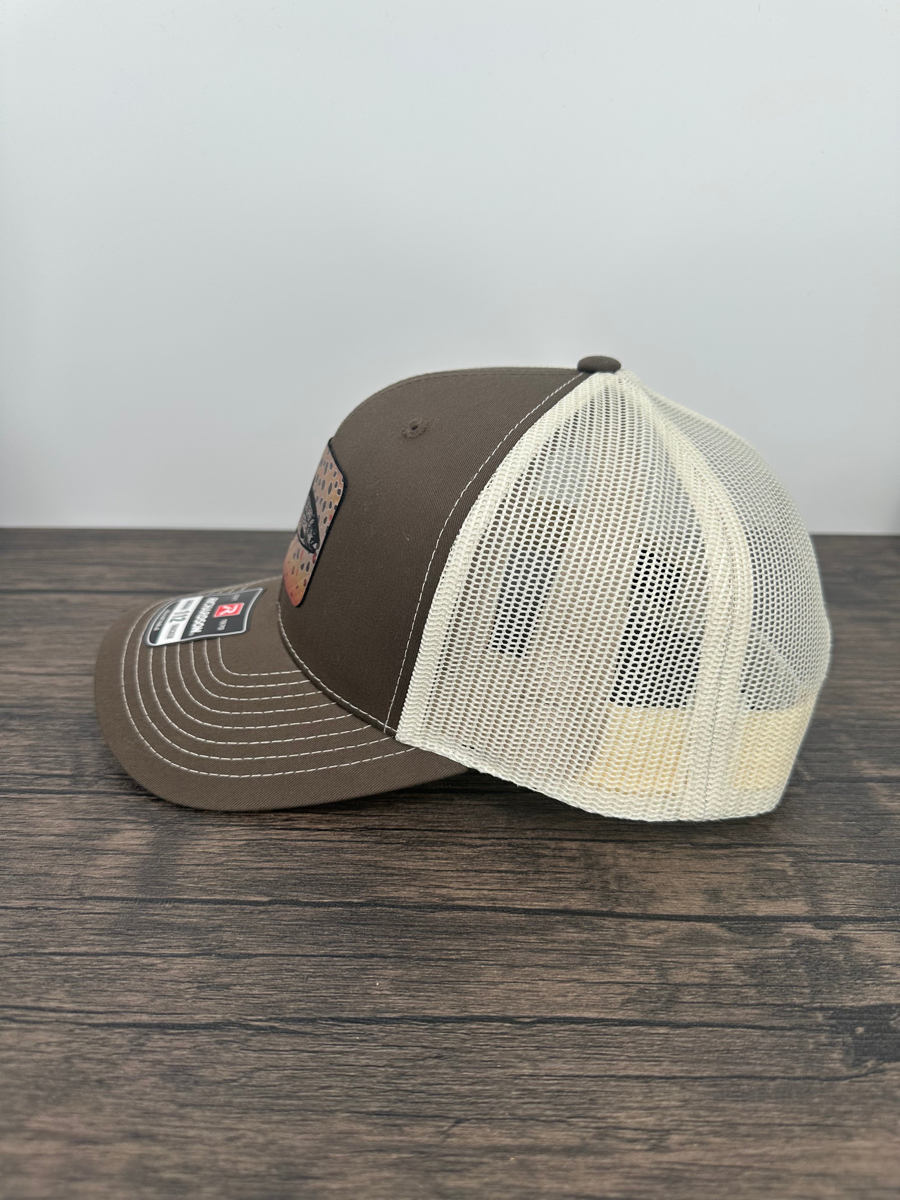 Side view of a Brown and beige brown trout fly fishing hat featuring a laser engraved trout outline on a printed brown trout patch