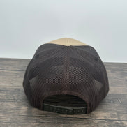 Black and beige bear patch cap on a wooden surface with a white background
