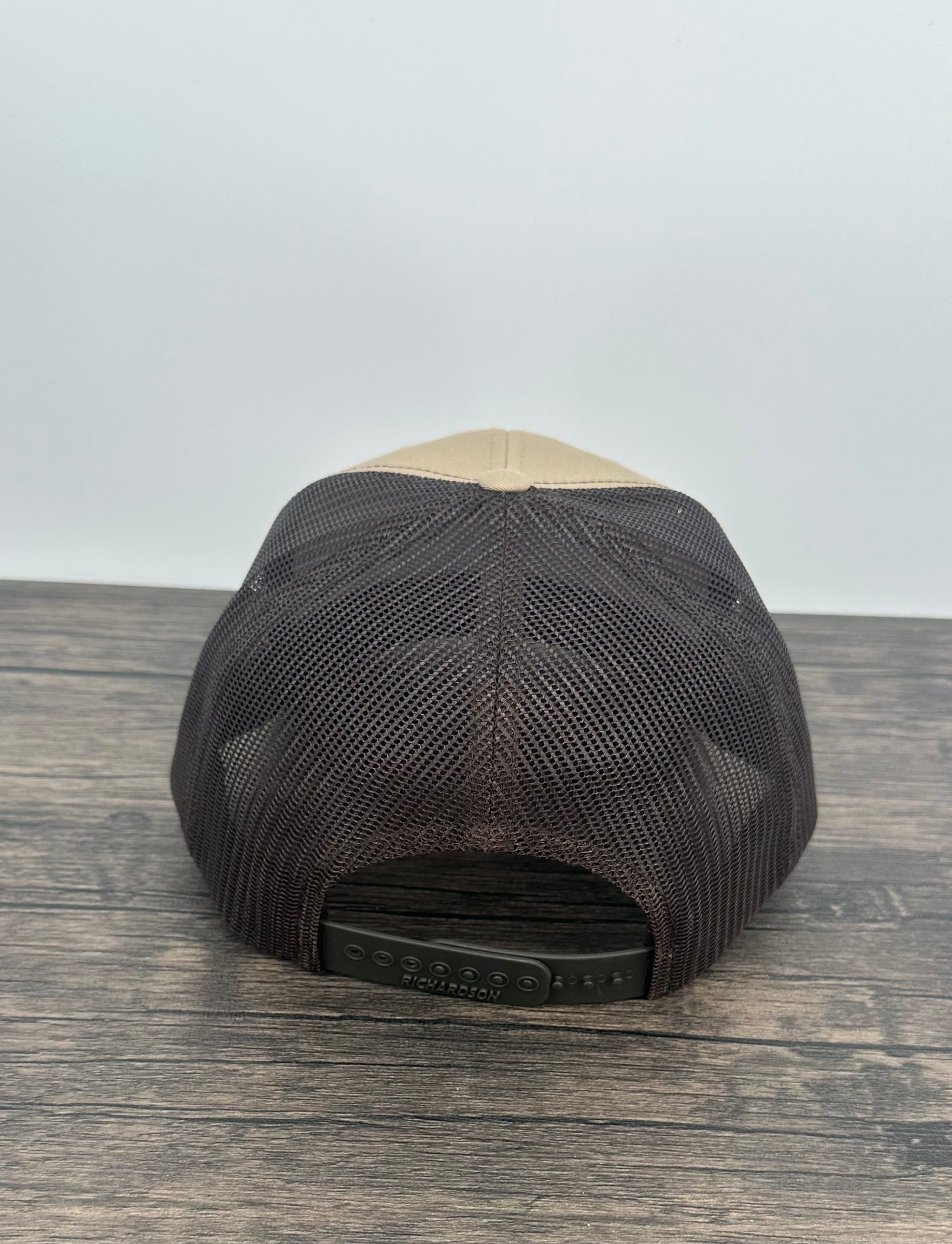 Black and beige bear patch cap on a wooden surface with a white background