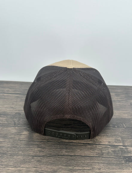 Black and beige bear patch cap on a wooden surface with a white background
