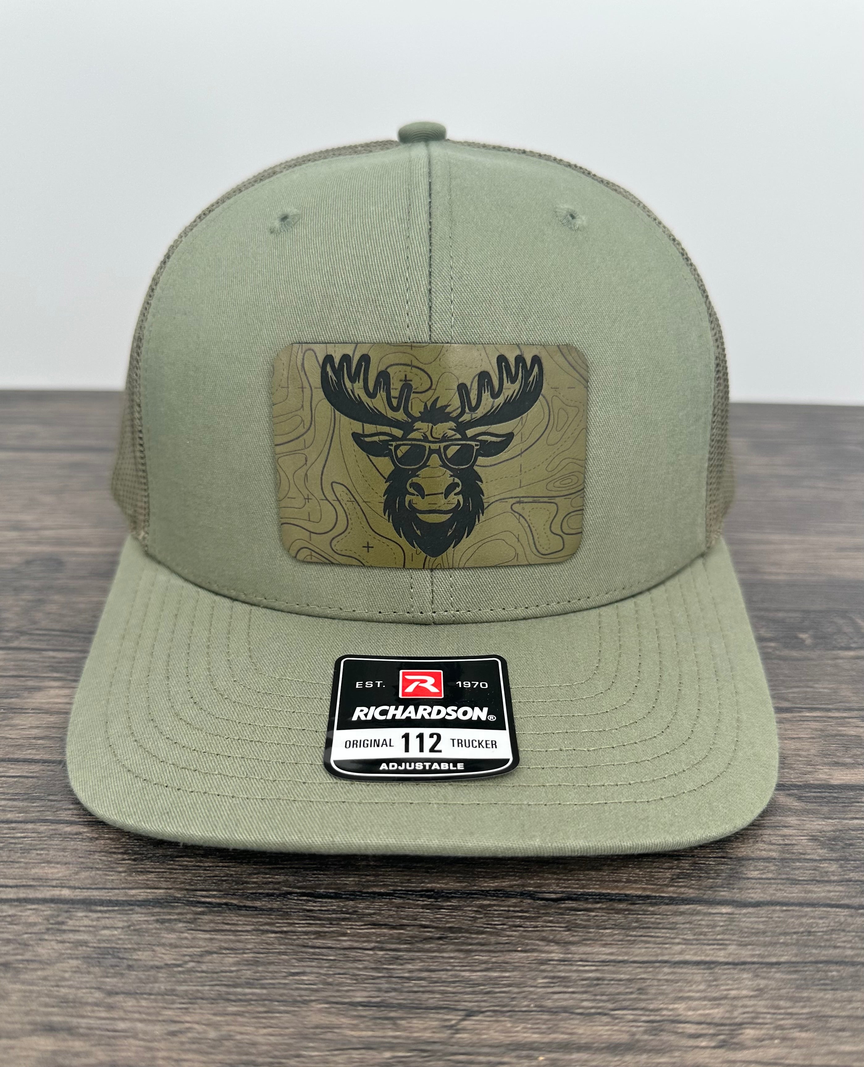 Green cap with a  moose wearing sunglasses  patch