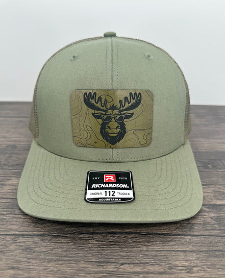 Green cap with a  moose wearing sunglasses  patch