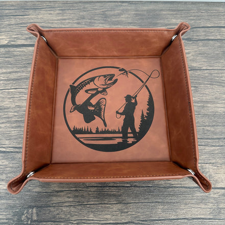 Brown leather tray with fish and fly fishing design on a wooden surface