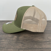 Side view of a Green and beige trucker hat with moose  wearing a beanie and sunglasses that has been laser engraved on a leatherette patch on the front of the hat