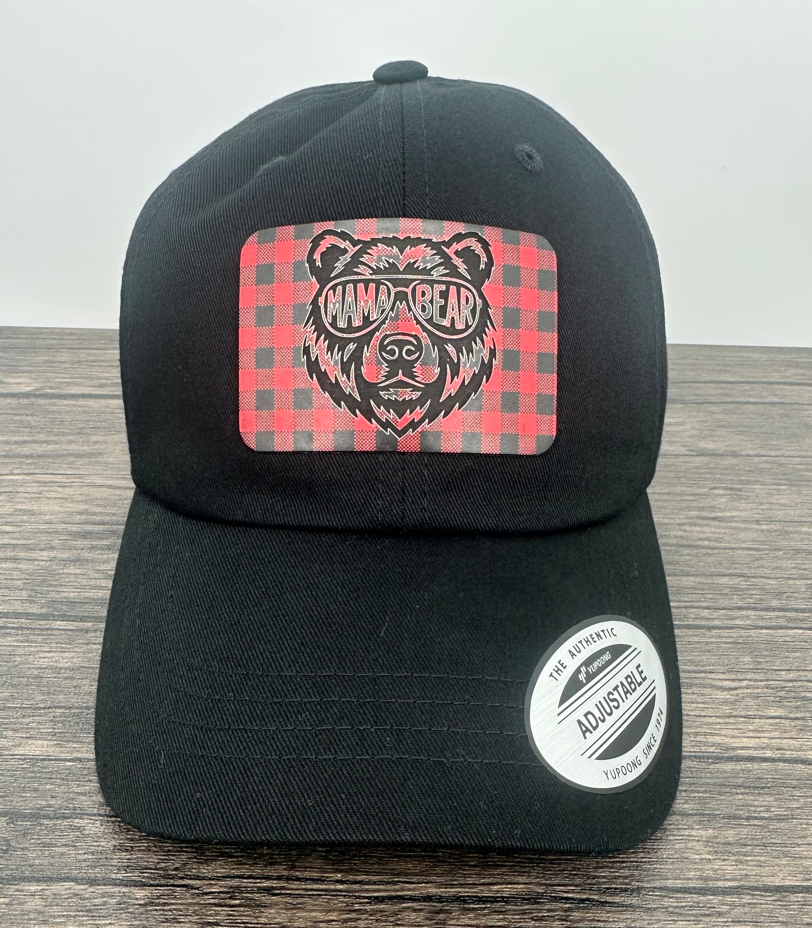 Black hat with a red and black buffalo plaid patch that has mama bear engraved on the patch
