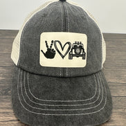 Black and white cap with a patch featuring hand signs, a heart, and a jeep on a wooden surface.