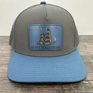 Gray and blue cap with a snake emblem and 'Don't Tread on Me' text on a wooden surface.