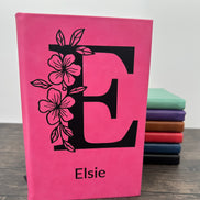 Pink laser engraved notebook with floral letter 'E' design and 'Elsie”  on the cover