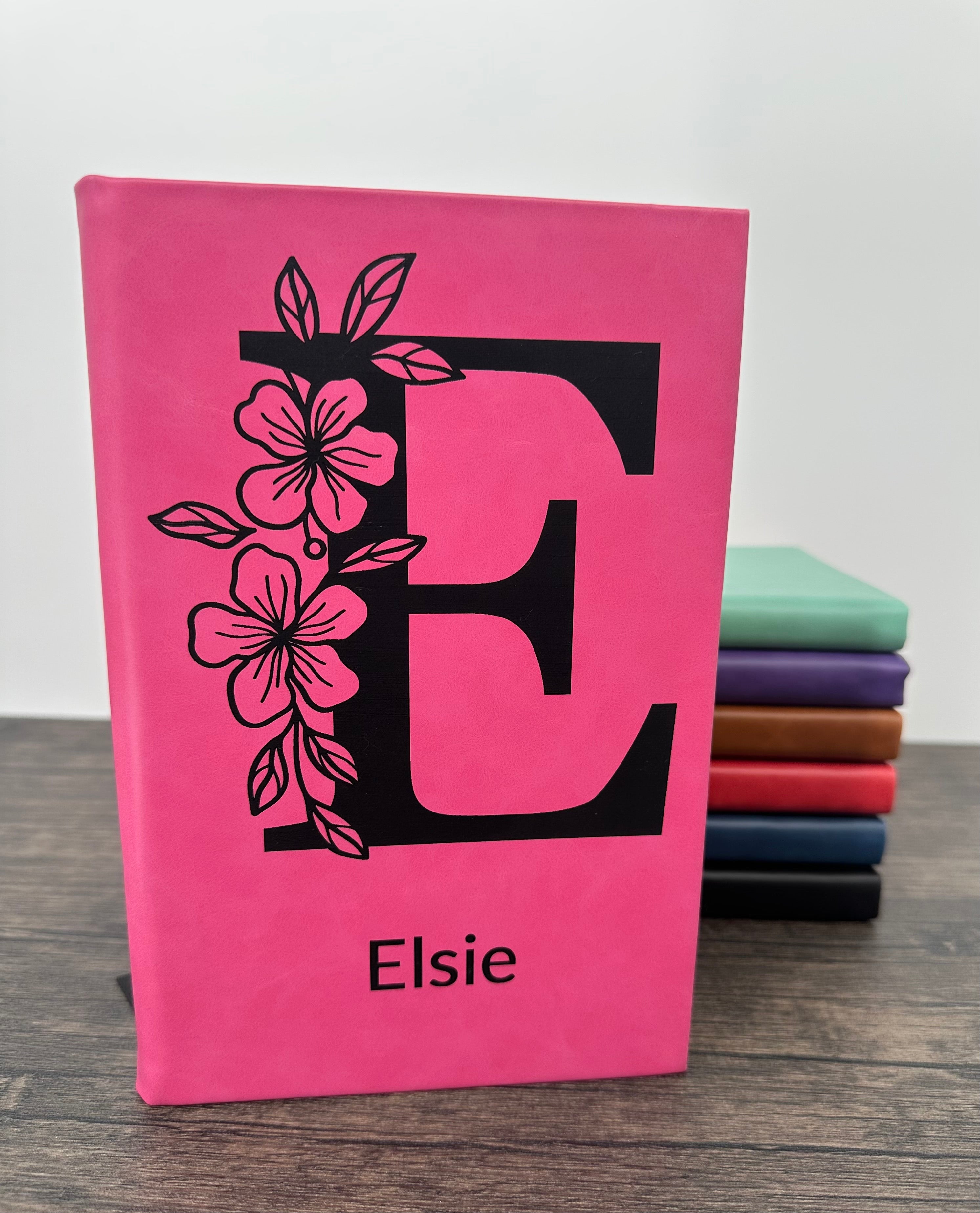 Pink laser engraved notebook with floral letter 'E' design and 'Elsie”  on the cover
