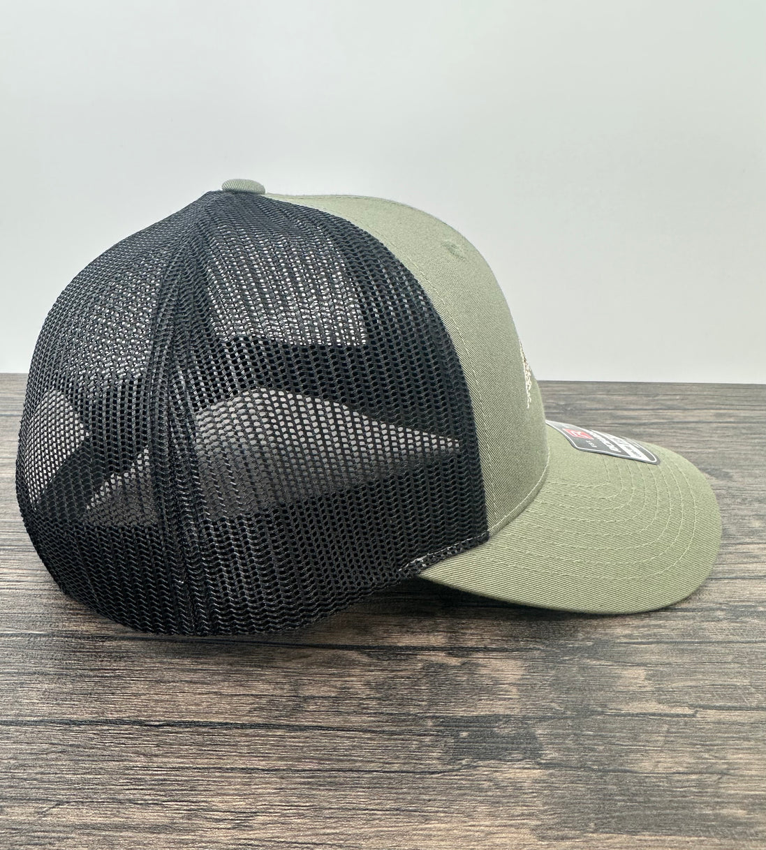 Side view of an embroidered fly fishing hat in green and black