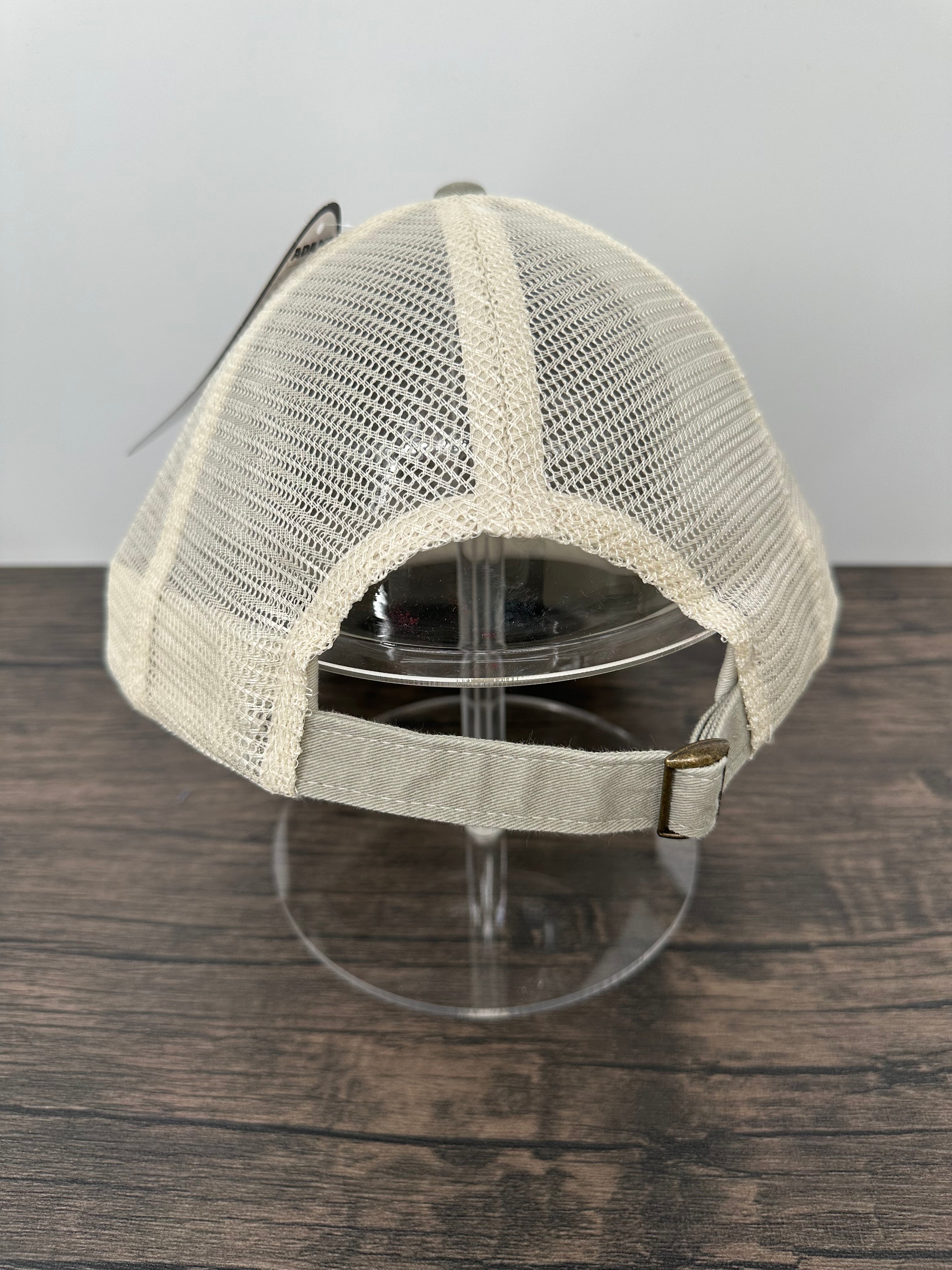 Beige mesh cap on a stand against a wooden panel background