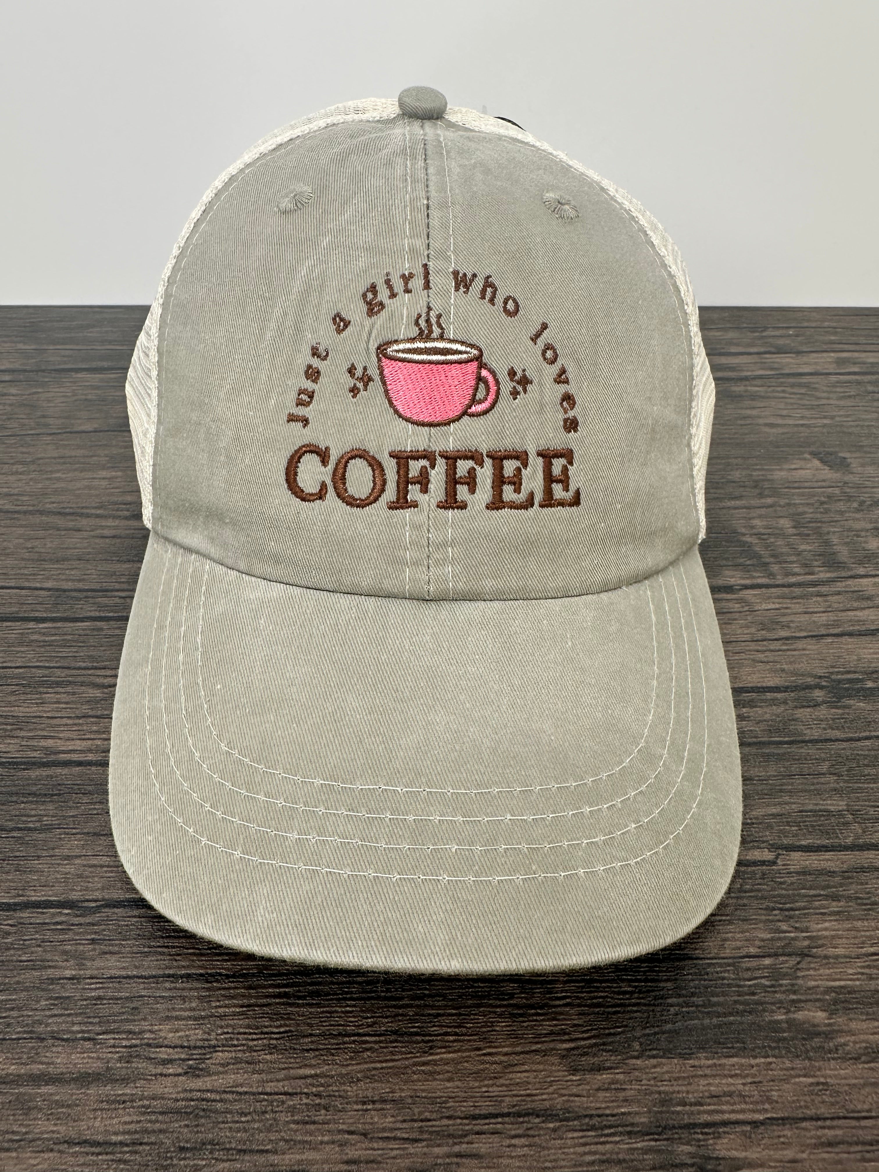 Beige cap with coffee-themed text and pink cup graphic on a wooden surface