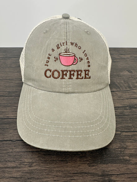 Beige cap with coffee-themed text and pink cup graphic on a wooden surface