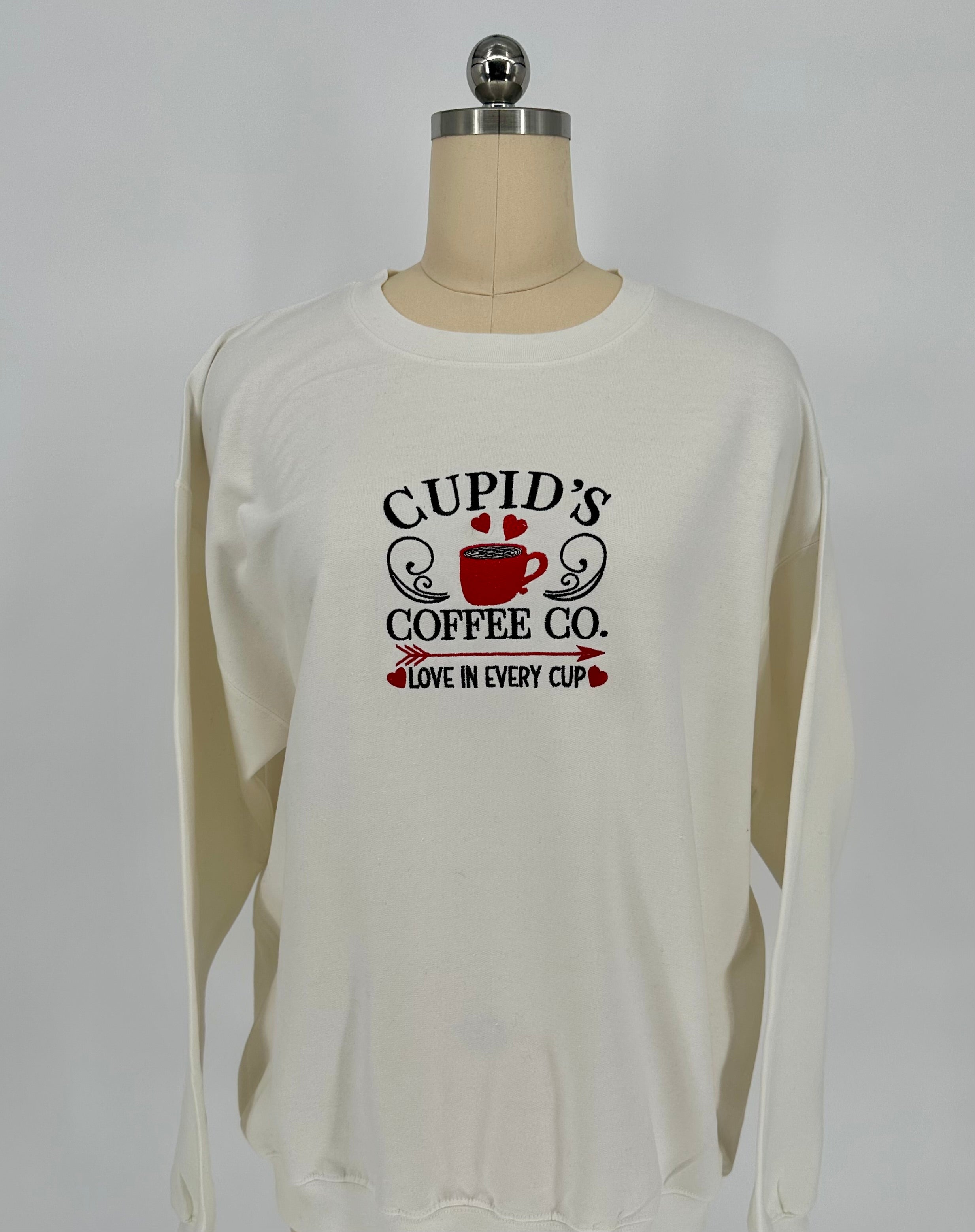 White long-sleeve shirt with 'Cupid's Coffee Co.' text on a mannequin against a white background