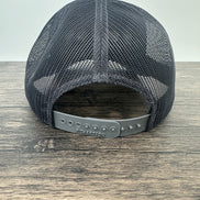 Black mesh cap on a wooden surface with a white background