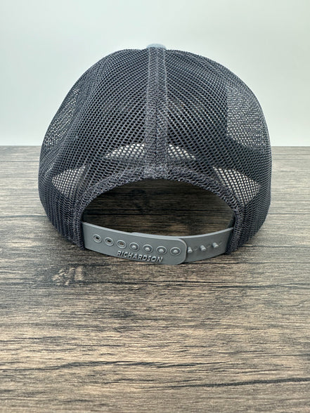 Black mesh cap on a wooden surface with a white background