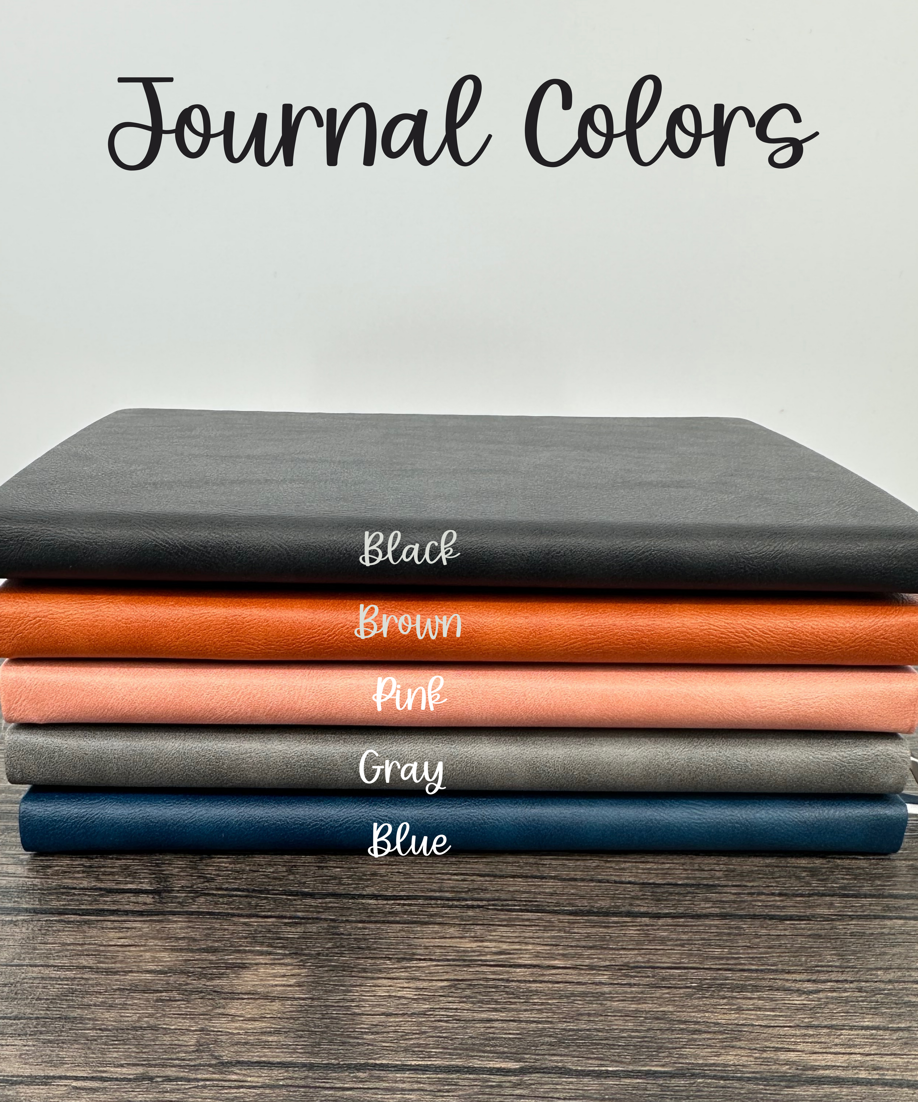 Stack of journals in various colors on a wooden surface with text indicating color names.
