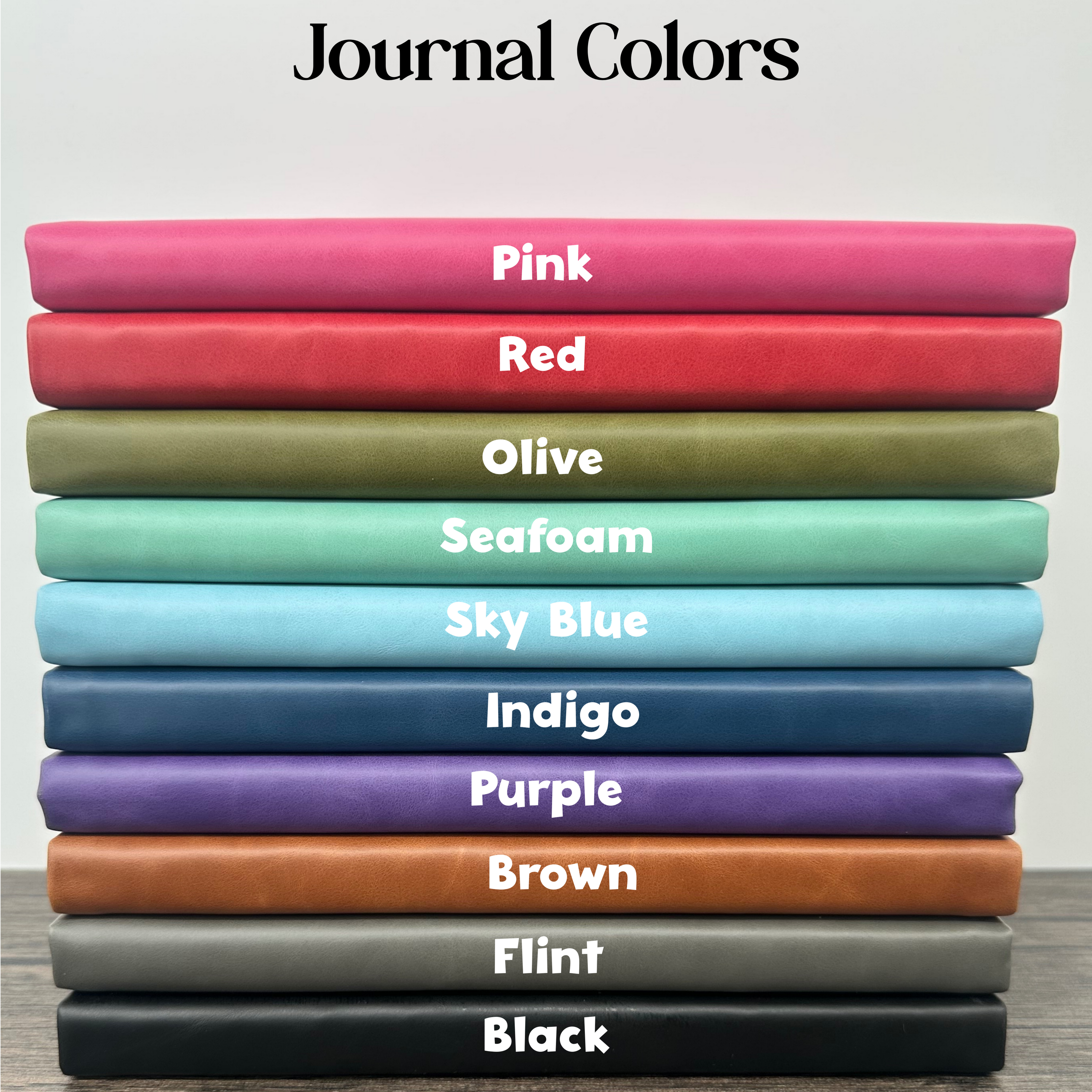 Stack of colorful journals with labels on a neutral background showing all the colors that are available for the custom journal from Doe River Designs