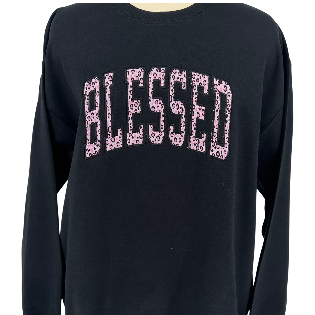 Black long-sleeve shirt with 'BLESSED' printed in pink leopard print on a white background