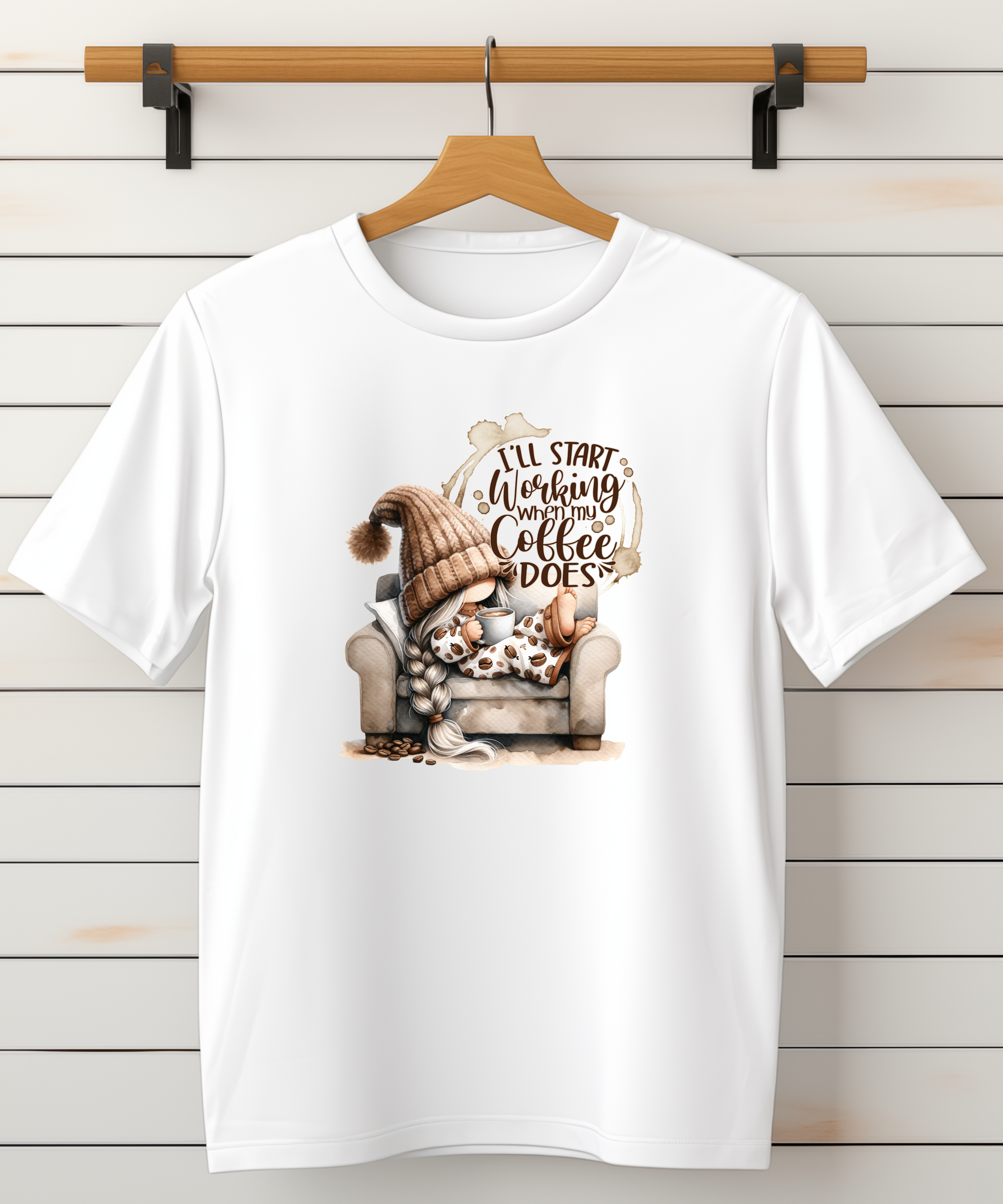 White t-shirt with a graphic of a gnome and text that says I’ll start working when my coffee does