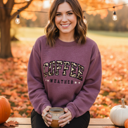 Model wearing light tan Coffee Weather sweatshirt with visible text